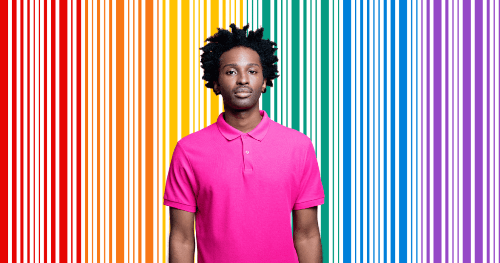 Una persona negra con una camiseta rosa sobre un fondo de filas delgadas con los colores de la bandera LGTBI, celebrando el día contra el acoso escolar y la discriminación.