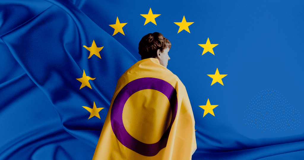 Una persona de espaldas, arropada con la bandera intersexual (amarilla con un círculo morado), observa de frente una gran bandera de la Unión Europea.